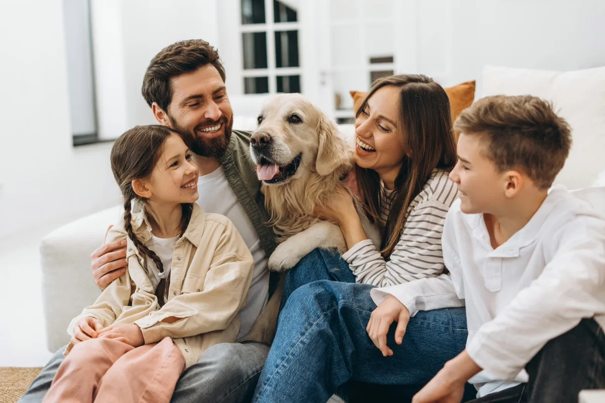 A family relaxing with their golden retriever in the living room of their rental home